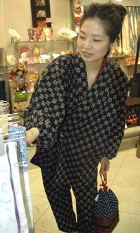 「ひっぱり」に「もんぺ」姿で、店内の商品を整理する女性スタッフ=神戸市中央区の三宮センター街の呉服店「本多屋」