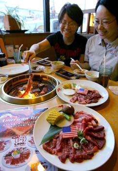米国産牛肉がメニューに復活し、笑顔で口に運ぶ来店客=29日、大阪府高槻市の「でん 柱本店」(撮影・早坂洋祐)