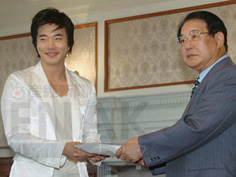 福岡県西方沖地震の義援金を麻生渡知事(右)に手渡す韓国人俳優のクォン・サンウさん=11日午前、福岡県庁