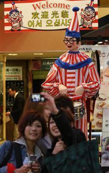「くいだおれ人形」の前では、一緒に写真を撮ろうとする人が絶えない=8日午後6時過ぎ、大阪市中央区