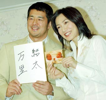 代理母による出産後、双子の男児の写真と名前を書いた色紙を持ち、記者会見する高田延彦さん、向井亜紀さん夫妻=15日午後3時すぎ、東京都港区のホテル